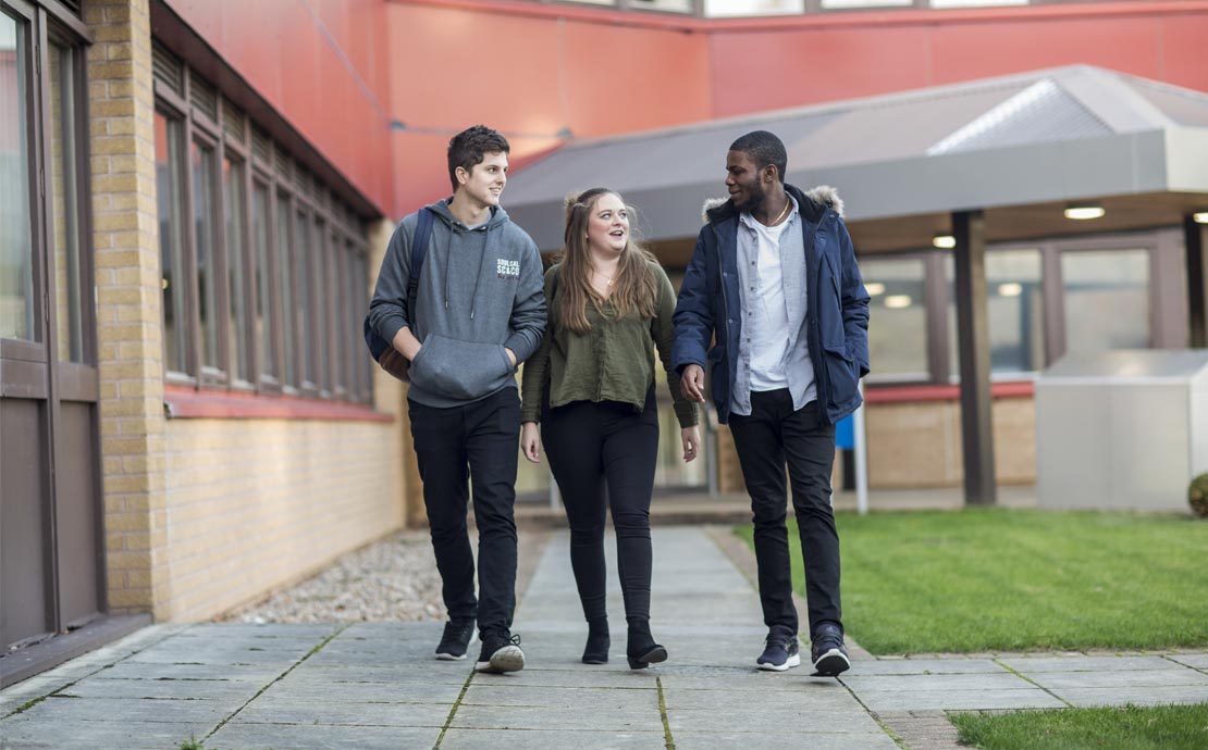 a group of students walking and smiling outside the Richard Price Building