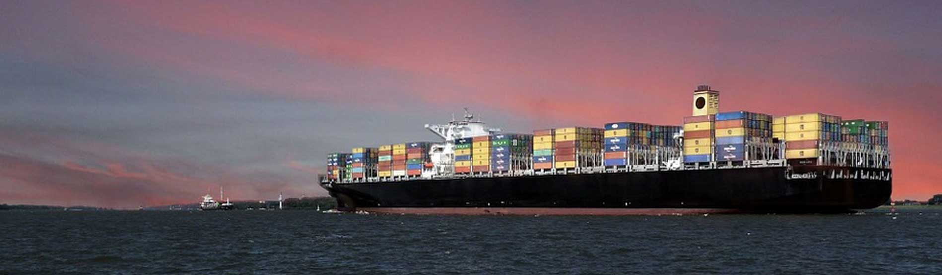 A container ship sailing at sun down, with a red sky