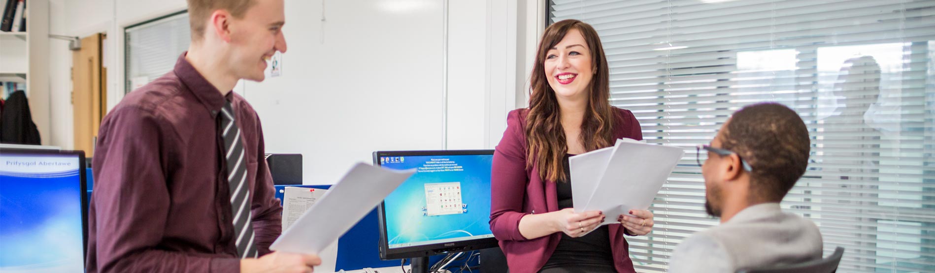 three research students in the postgraduate research room, talking about their work