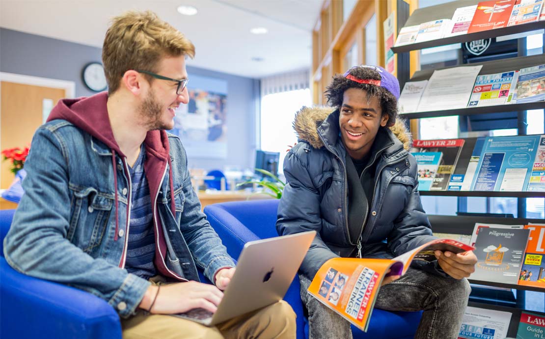 two students having a friendly chat in the atrium of the richard price building