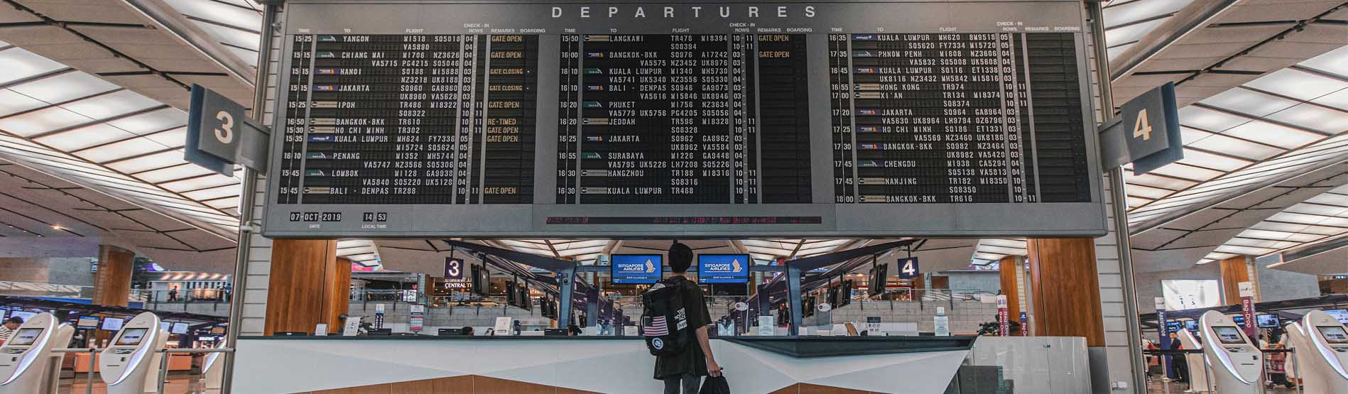 A student at an airport departure board