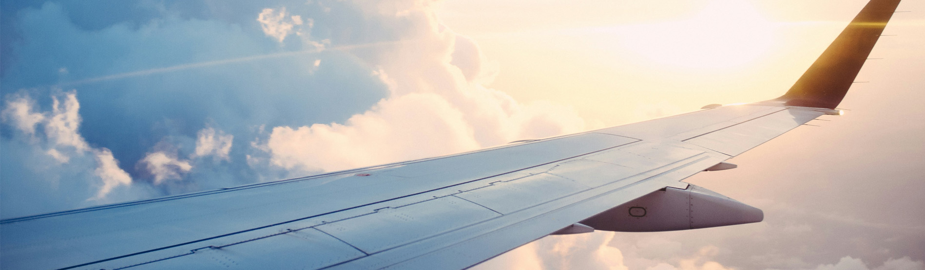 A plane wing at altitude with clouds