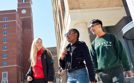 Three students walking through Bay Campus in the Sun