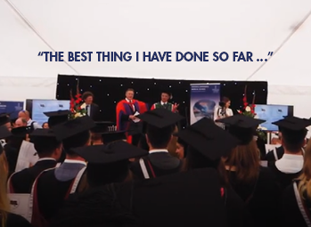 Students in graduations gowns, looking at the stage of Professors. 