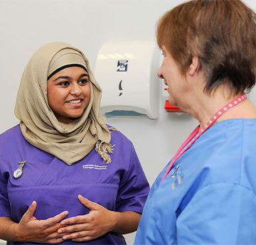 Two students seeing to a fake patient as part of their studies 