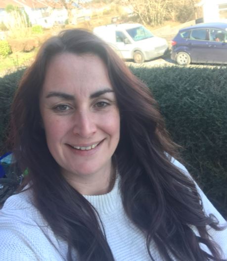 Woman with long brown hair taking selfie in garden