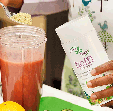 person using a teaspoon to add powdered tea into a fruit smoothie