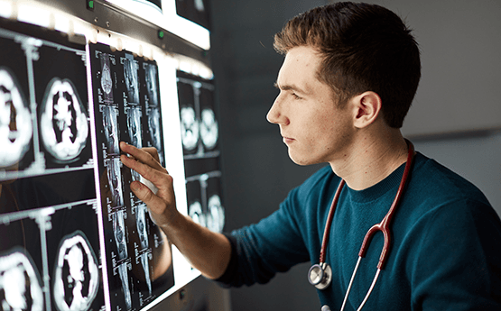 Alex Ruddy examining an xray with stethescope around his neck