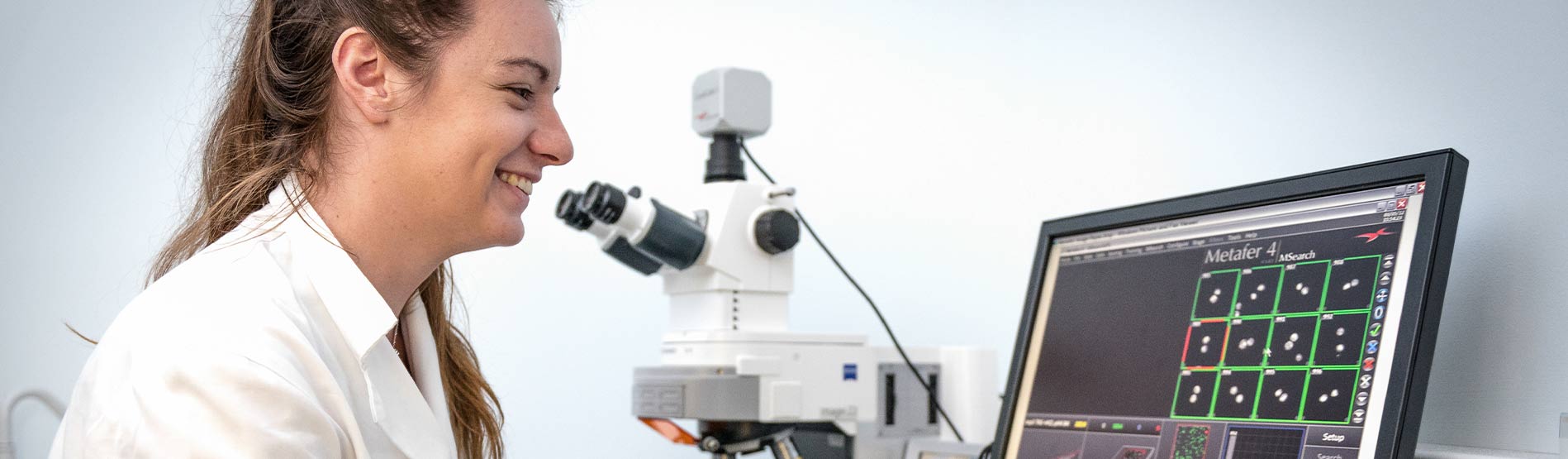 Research in Lab Coat looking at results on screen. 