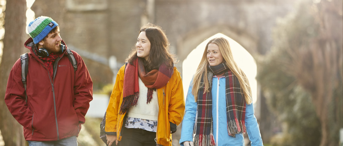 People walking through a park in winter, carrying bags or rucksacks