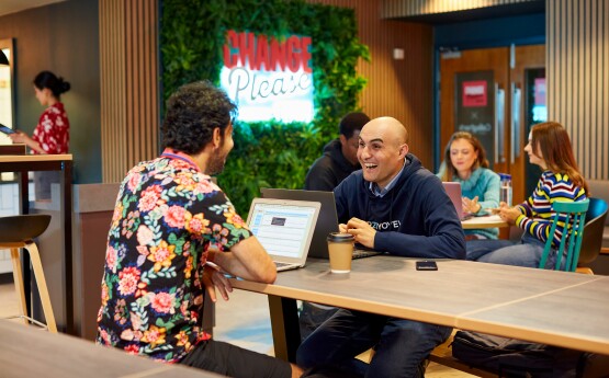 Two people sitting down with a coffee talking.