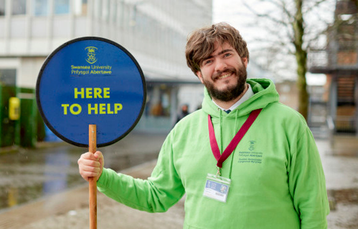 Student ambassador holding a 'Here to Help' sign