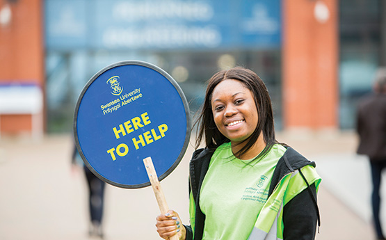 Student carrying a here to help sign