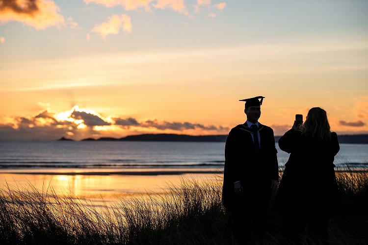 Sunset beach background with a student having a graduation photo