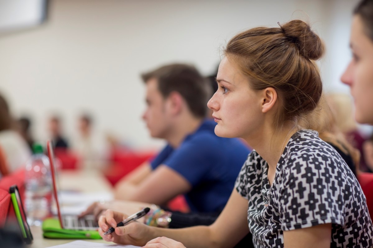 Female student sitting in lecture theatre and listening intently.