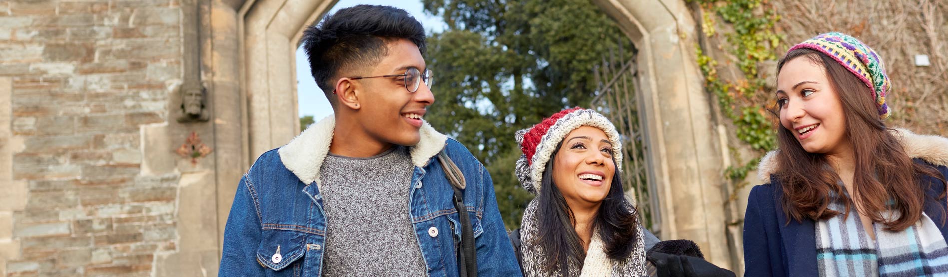 3 students walking through the park in the cold.