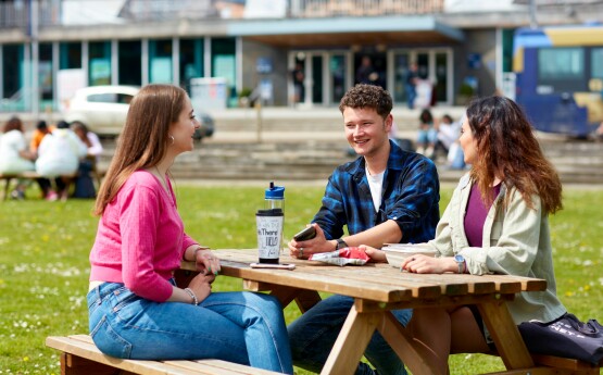 3 students sitting on a table outside Fulton House