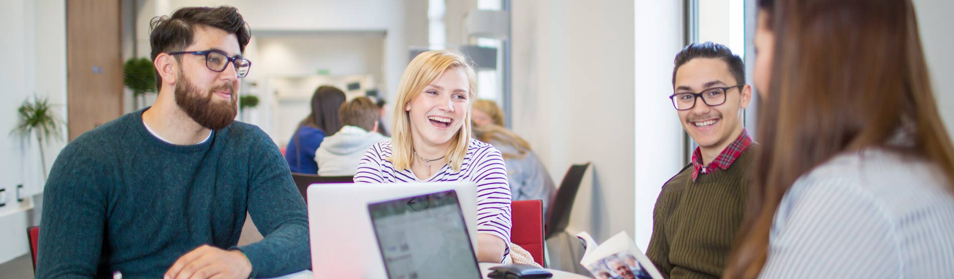 Students laughing at a study table in the Bay Campus.