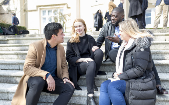 Male and female students sitting on the steps outside the Abbey. 