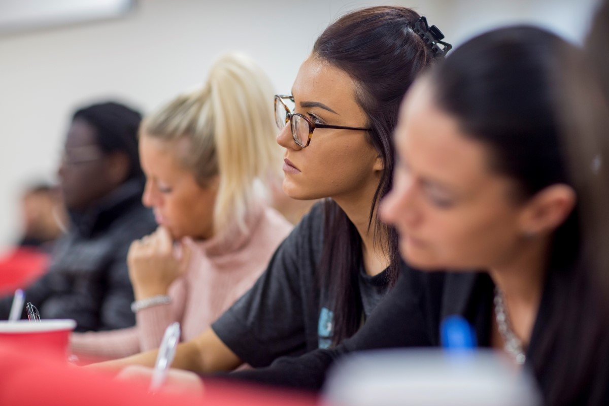 Female students sitting in lecture theatre and paying attention to lecturer.