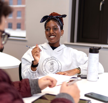 A smiling student collaborates with a fellow student