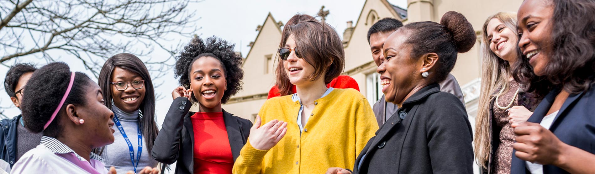 a group of smiling and laughing postgraduate students on the steps outside the abbey building