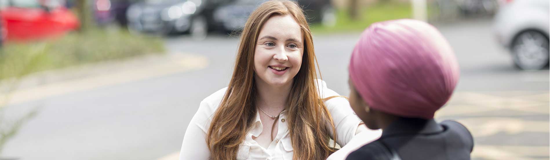 students speaking on a bench outside the Richard Price Building