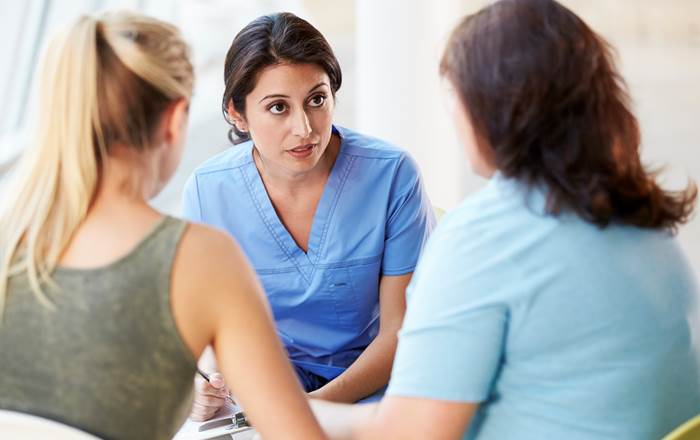 Health professional talking to parent and teenager.