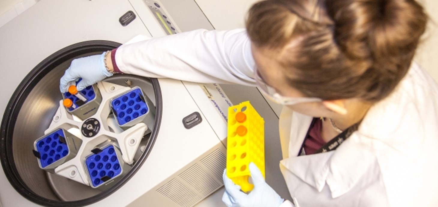 Picture shows samples being put into a centrifuge, an instrument used to separate sample components. 