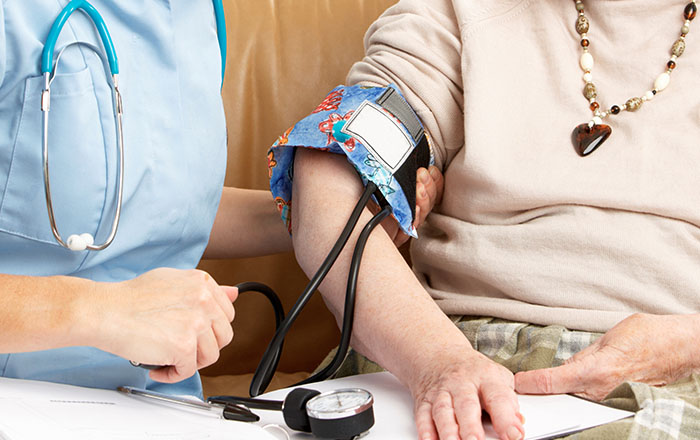 An elderly woman having her blood pressure taken by a nurse in her home 