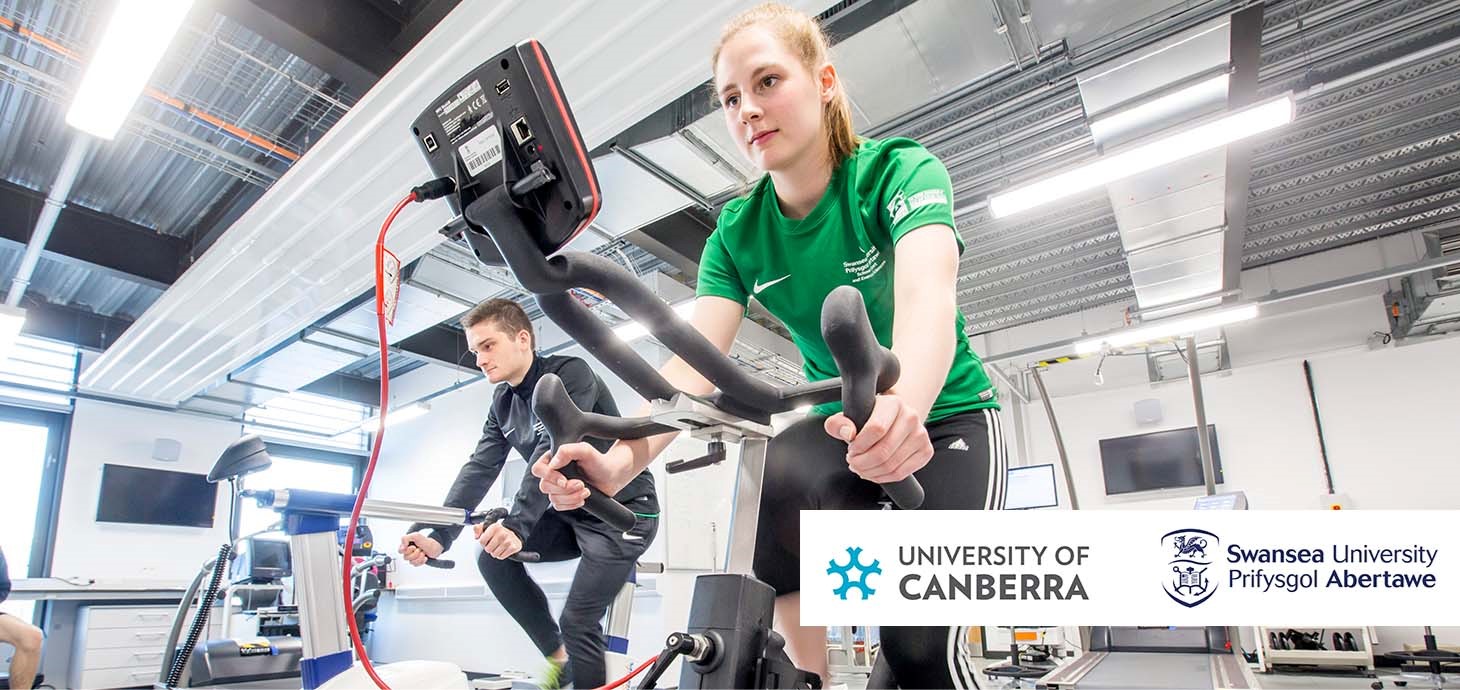 Two people on exercise bikes in a sports science laboratory: sport and exercise science experts from Swansea and the University of Canberra (UC) in Australia have launched an official partnership which will see them collaborate on research, teaching and student exchanges.