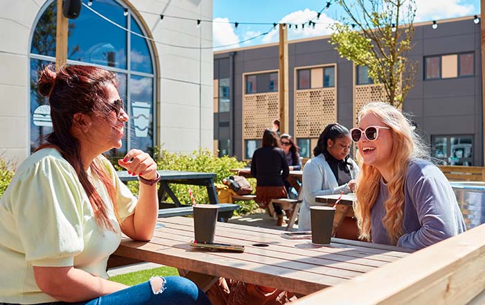 Students at the Bay Campus sitting outside a cafe