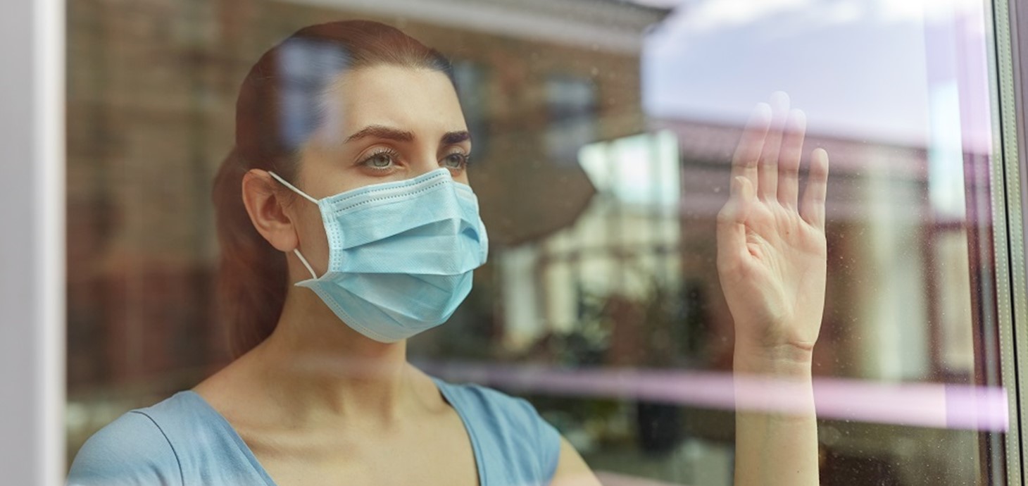 Woman wearing mask at window: people with long Covid experience a wide variety of ongoing problems such as tiredness and difficulty with everyday tasks, meaning they can struggle to return to their former lives.