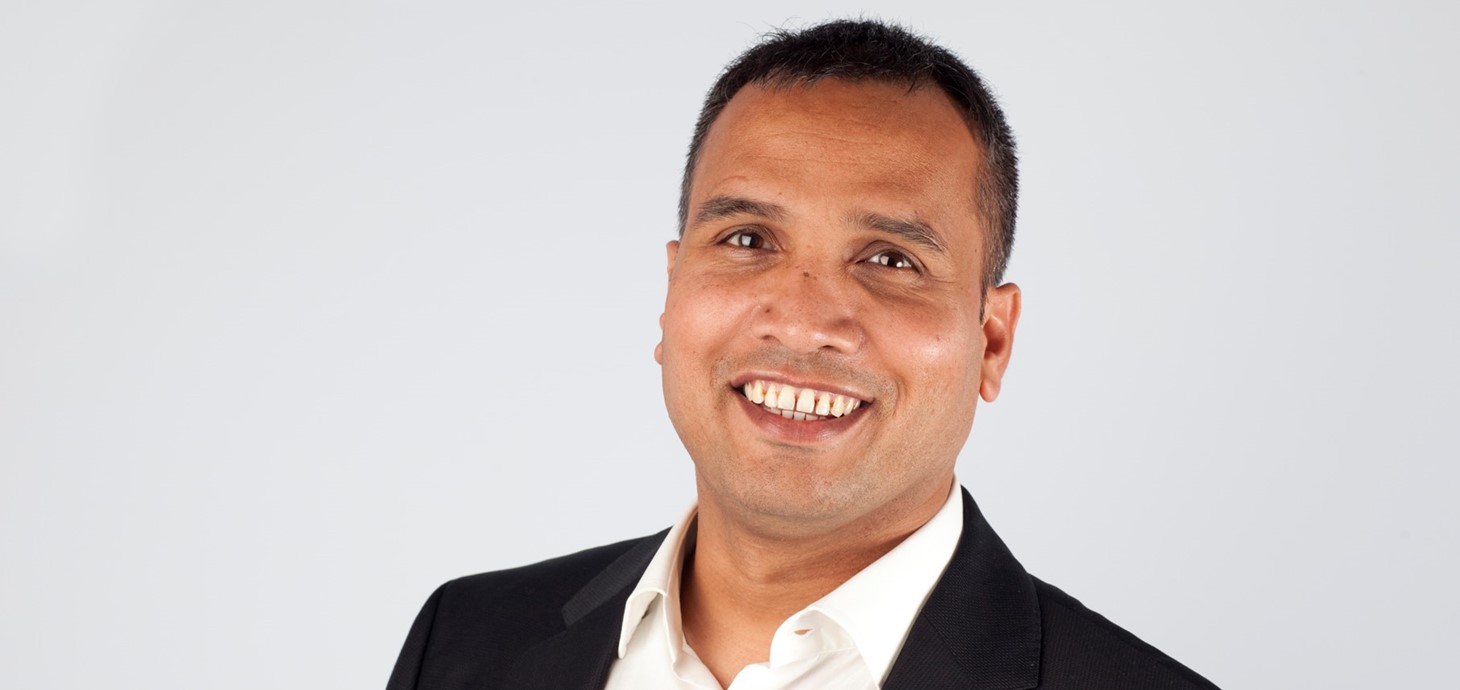 Close up picture of smiling man wearing dark suit and a white shirt.