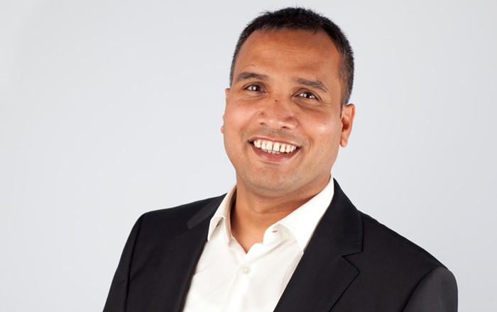 Close up picture of smiling man wearing dark suit and a white shirt.