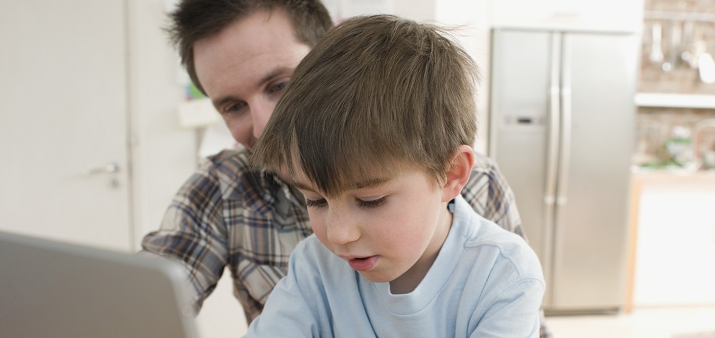 Father and son at a computer: children who live with a parent who has depression are more likely to develop depression and to not achieve educational milestones, according to a new study