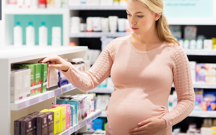 Pregnant woman in a pharmacy looking at medication