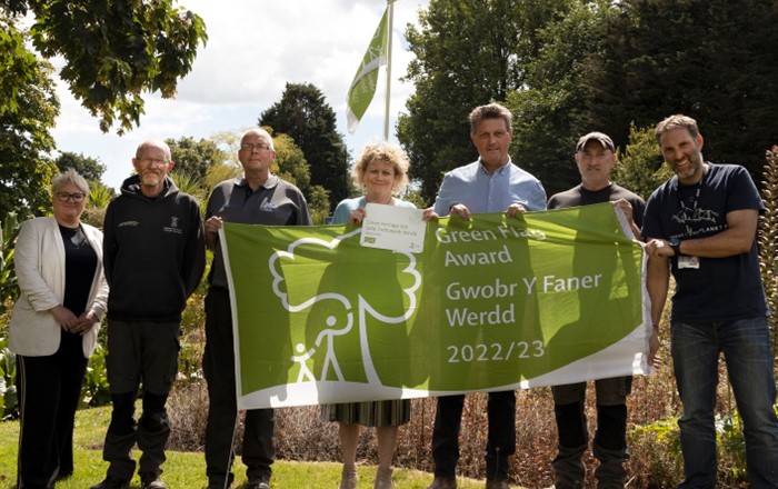 Group of people outside standing in a line holding a green flag