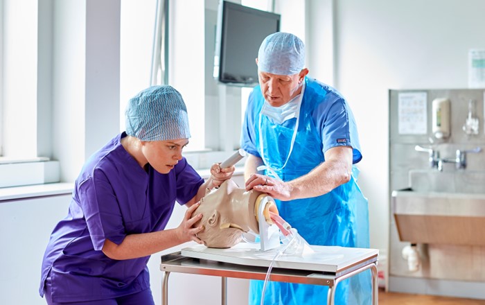 Two people wearing scrubs in a clinical room