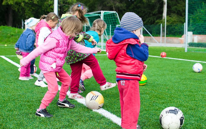 Group of small children on a pitch kicking footballs