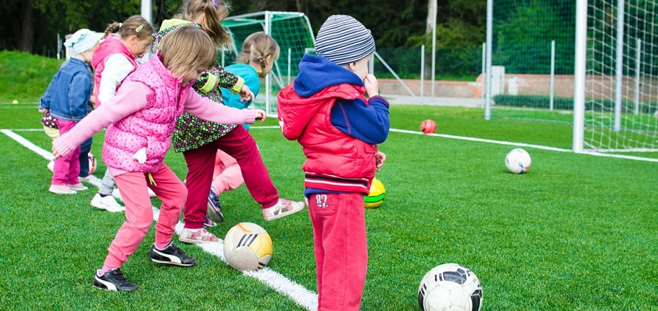 Group of small children on a pitch kicking footballs