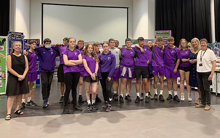 Group of school pupils standing in line in a school hall with two teachers