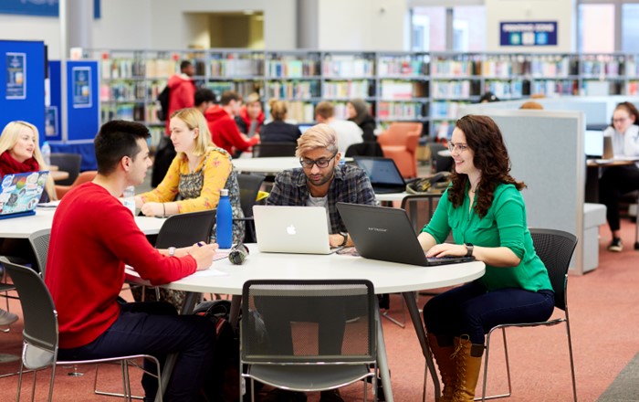 A group of students sat at a table using laptops