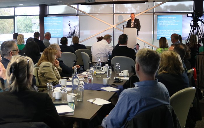 Man standing at a podium delivering a speech to a room of people