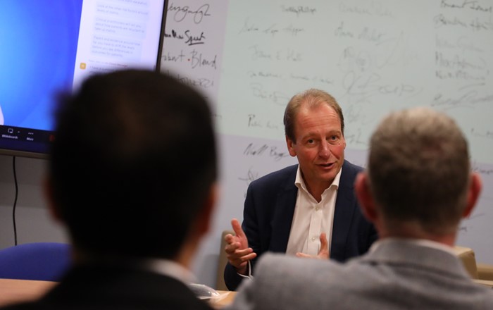 Man sitting in a meeting room seen between two people