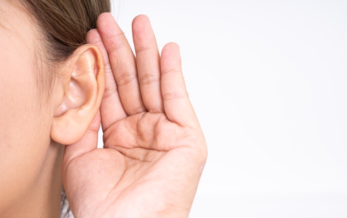 A person cupping their hand behind their ear.