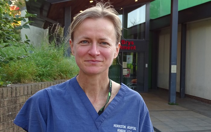 Woman in scrubs standing outside building