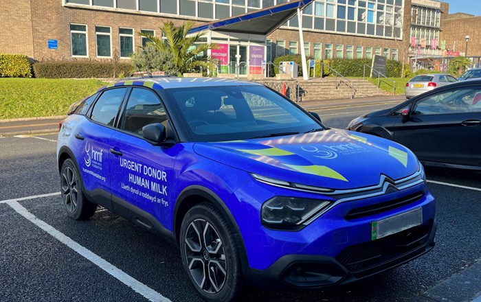 Blue electric saloon car outside building