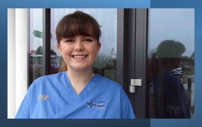 Close up head and shoulders picture of nurse wearing scrubs standing in front of glass door