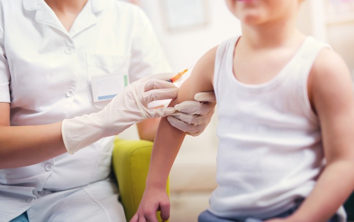 Child in vest being given vaccination in the army by a healthcare professional 